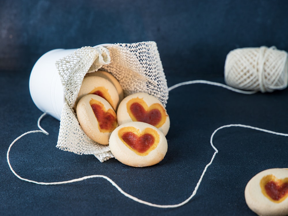 a bag of heart shaped cookies next to a couple of balls of string