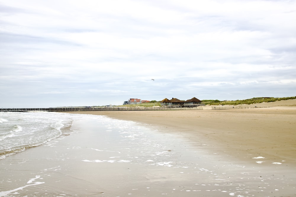 a sandy beach next to the ocean under a cloudy sky