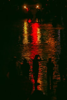 a group of people standing in the rain at night