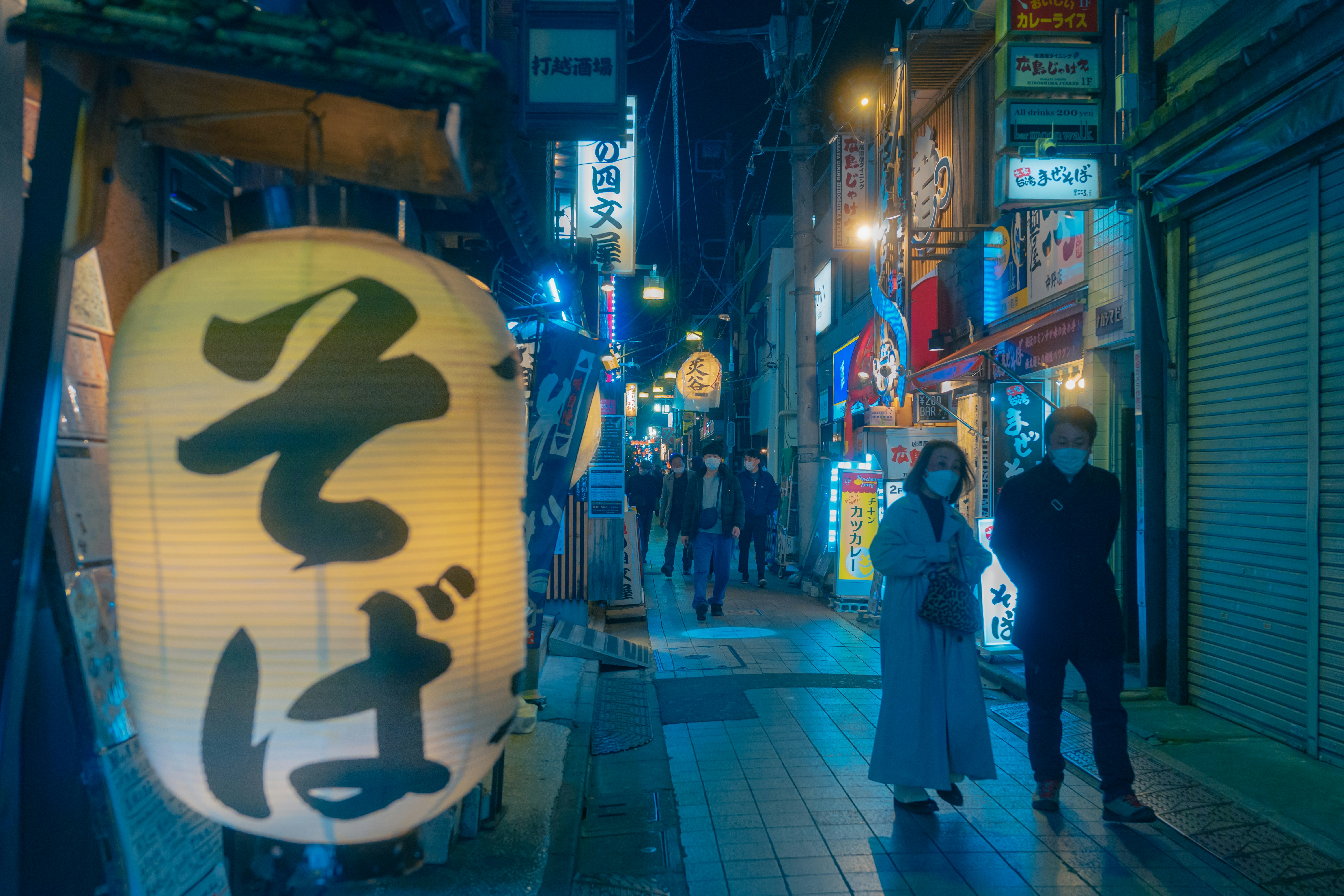 a couple of people walking down a street at night