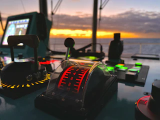 Close-up of a ship's electrical control panel with illuminated switches and gauges.