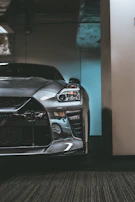 Side profile of a sleek restored coupe with metallic gray paint and gold accents gleaming in the garage.