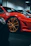 Close-up of a luxury sports car with a freshly painted deep red finish under dramatic garage lighting.