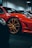 A close-up view of a luxurious red sports car with gold rims, parked indoors. The sleek body design and glossy finish emphasize its high-end nature.