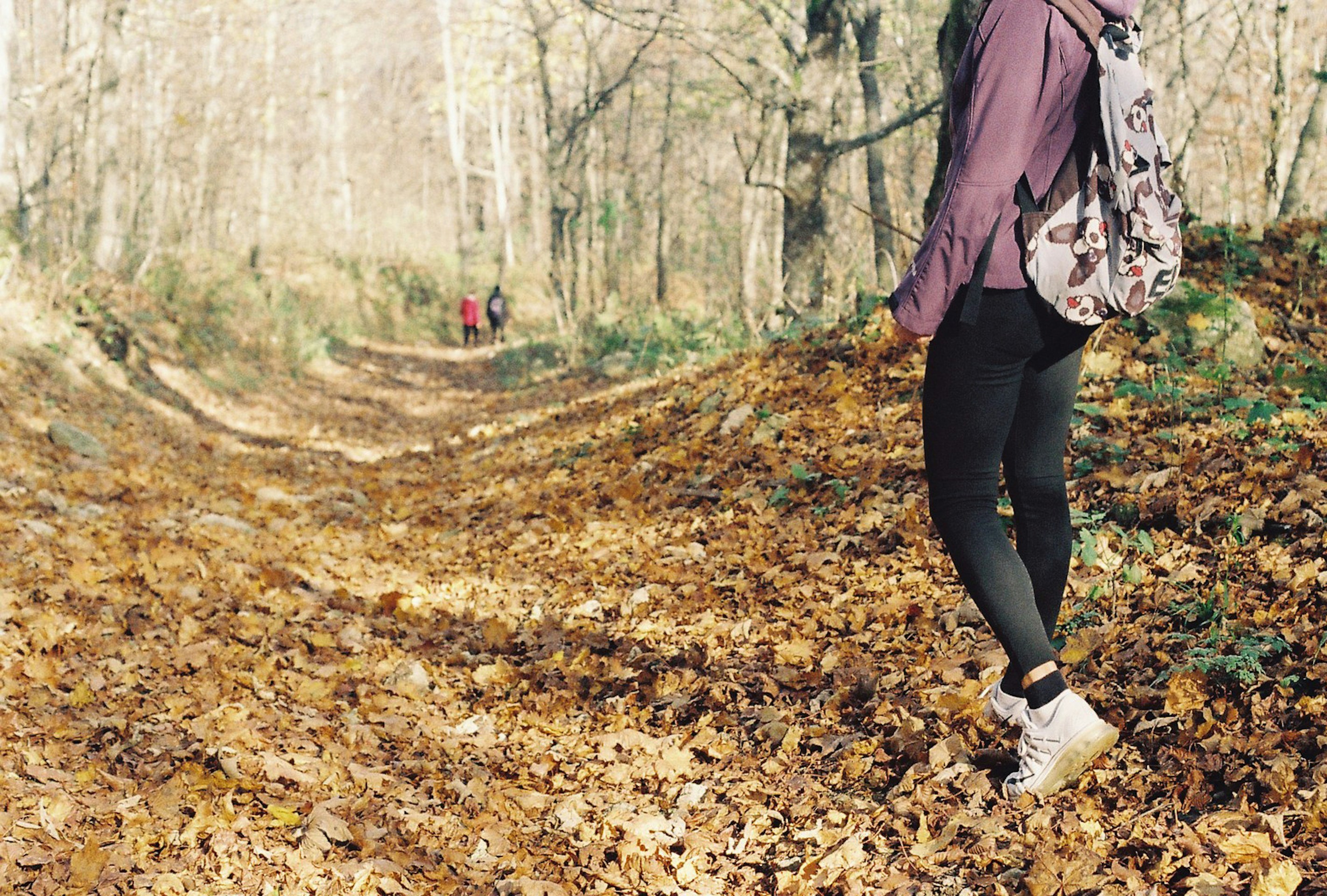 Una mujer caminando por un sendero cubierto de hojas