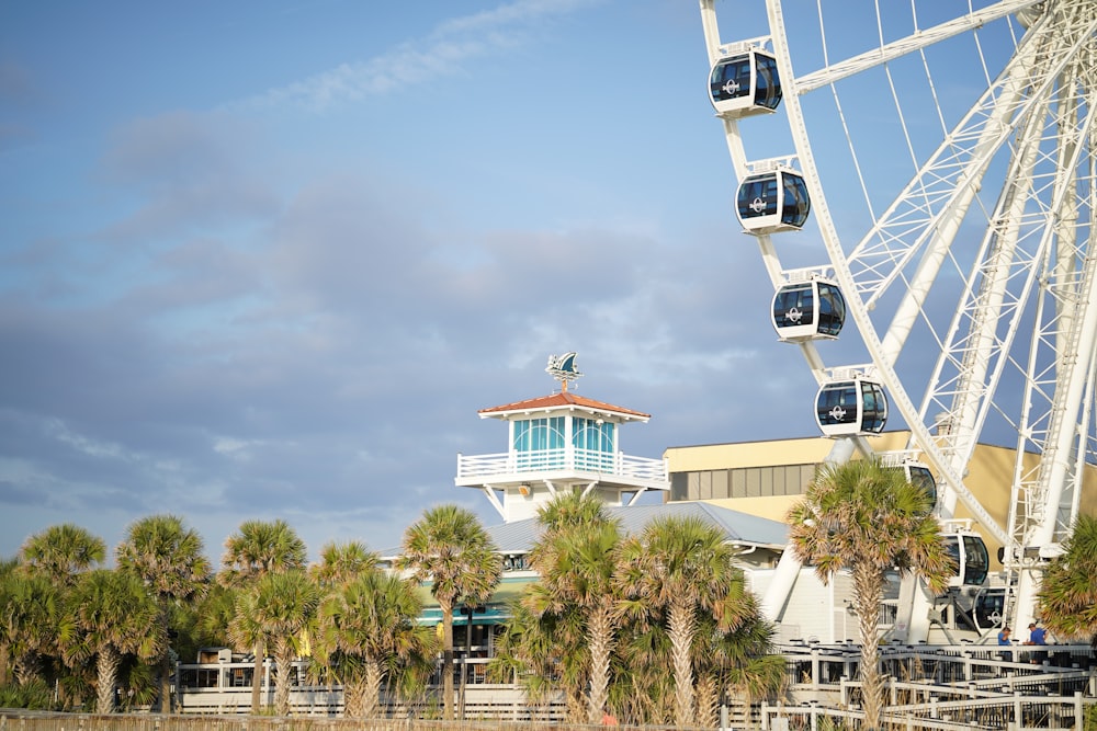 une grande roue assise à côté d’un bâtiment et de palmiers