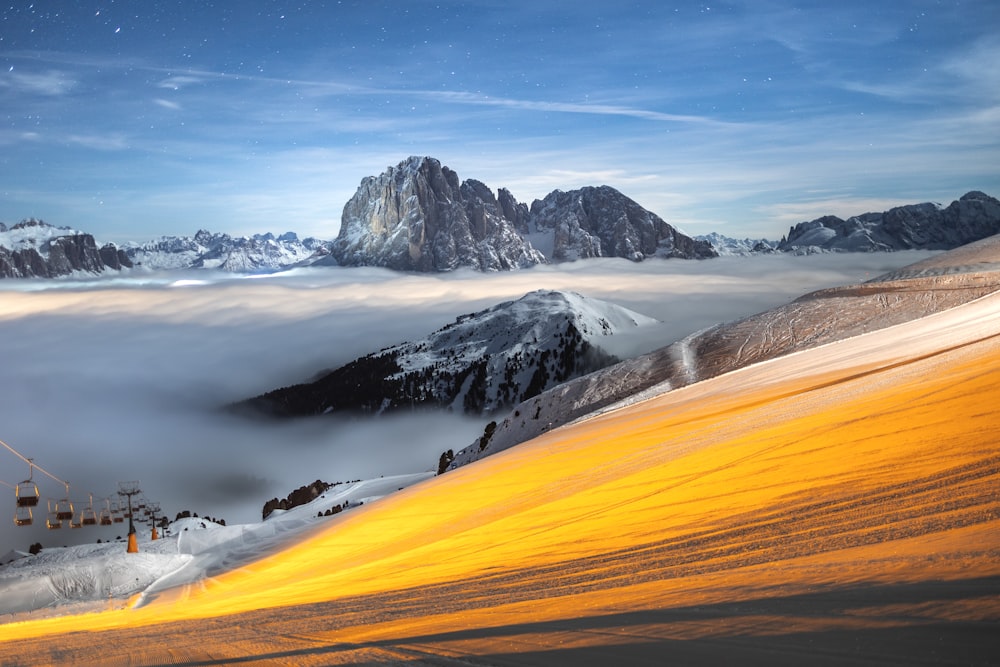 a mountain covered in snow and clouds under a blue sky