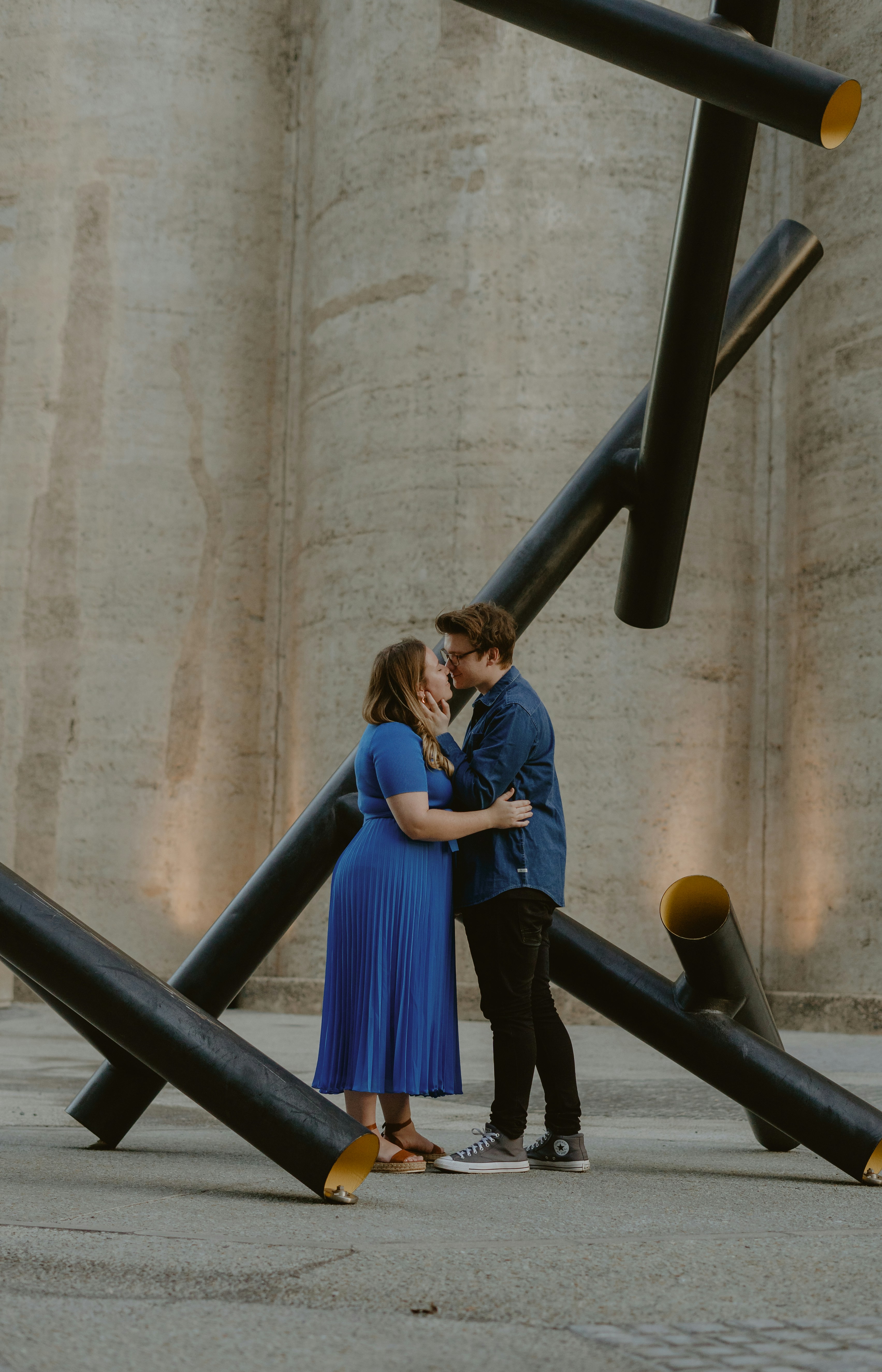 a man and woman standing in front of a sculpture