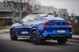 a blue bmw X6 suv parked on the side of the road