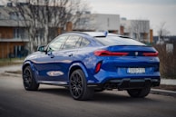 a blue bmw X6 suv parked on the side of the road