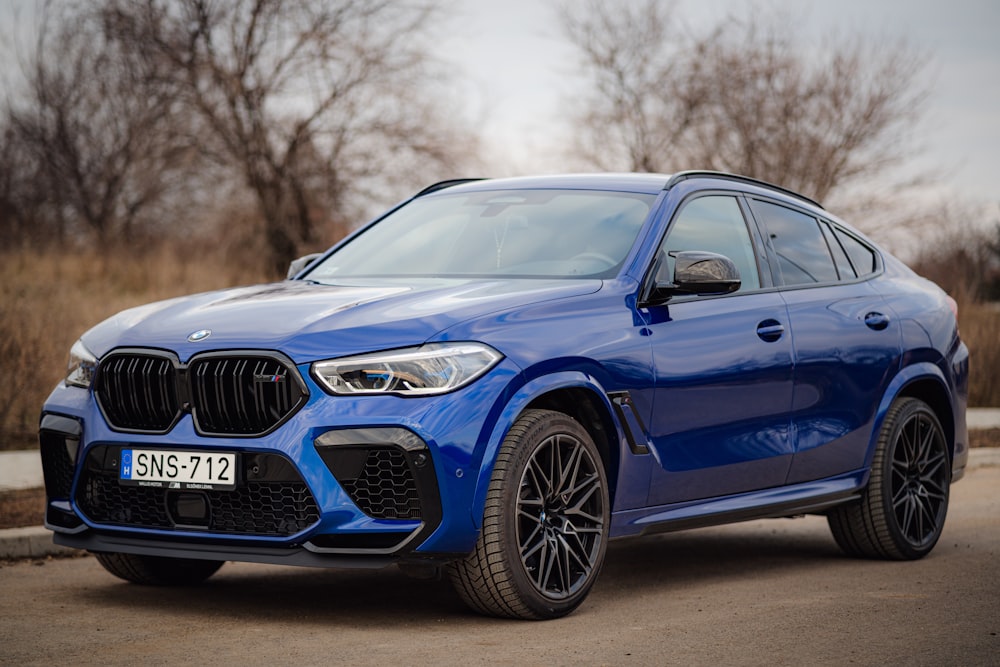 a blue bmw suv parked on the side of the road