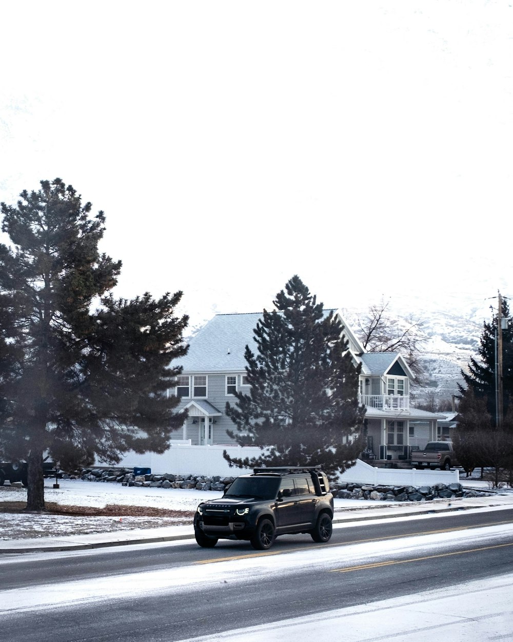 a black truck driving down a snow covered road