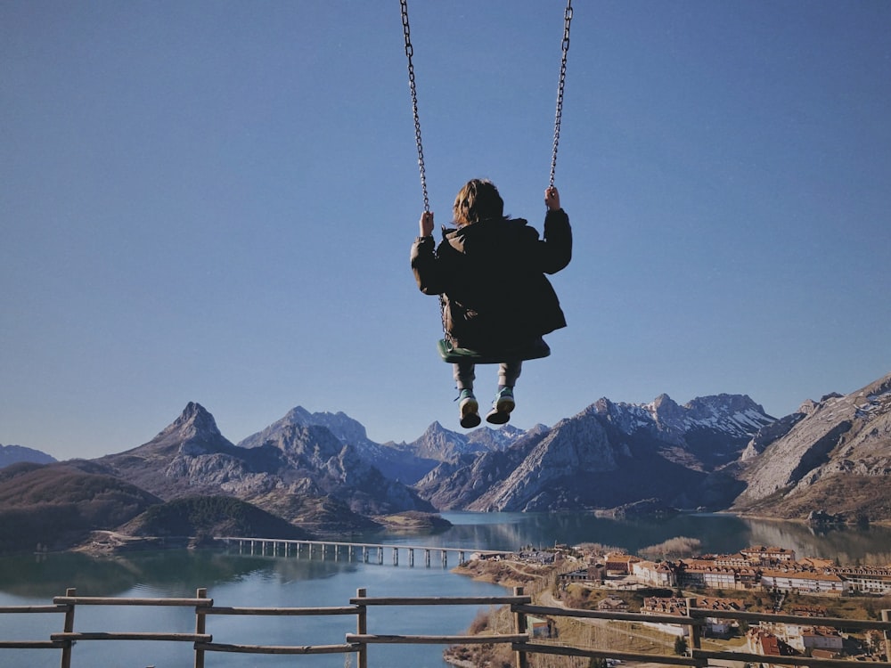 a person swinging on a rope over a body of water