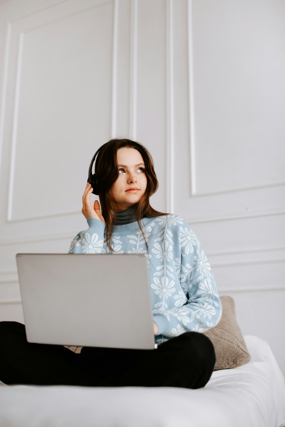 a woman sitting on a bed using a laptop computer