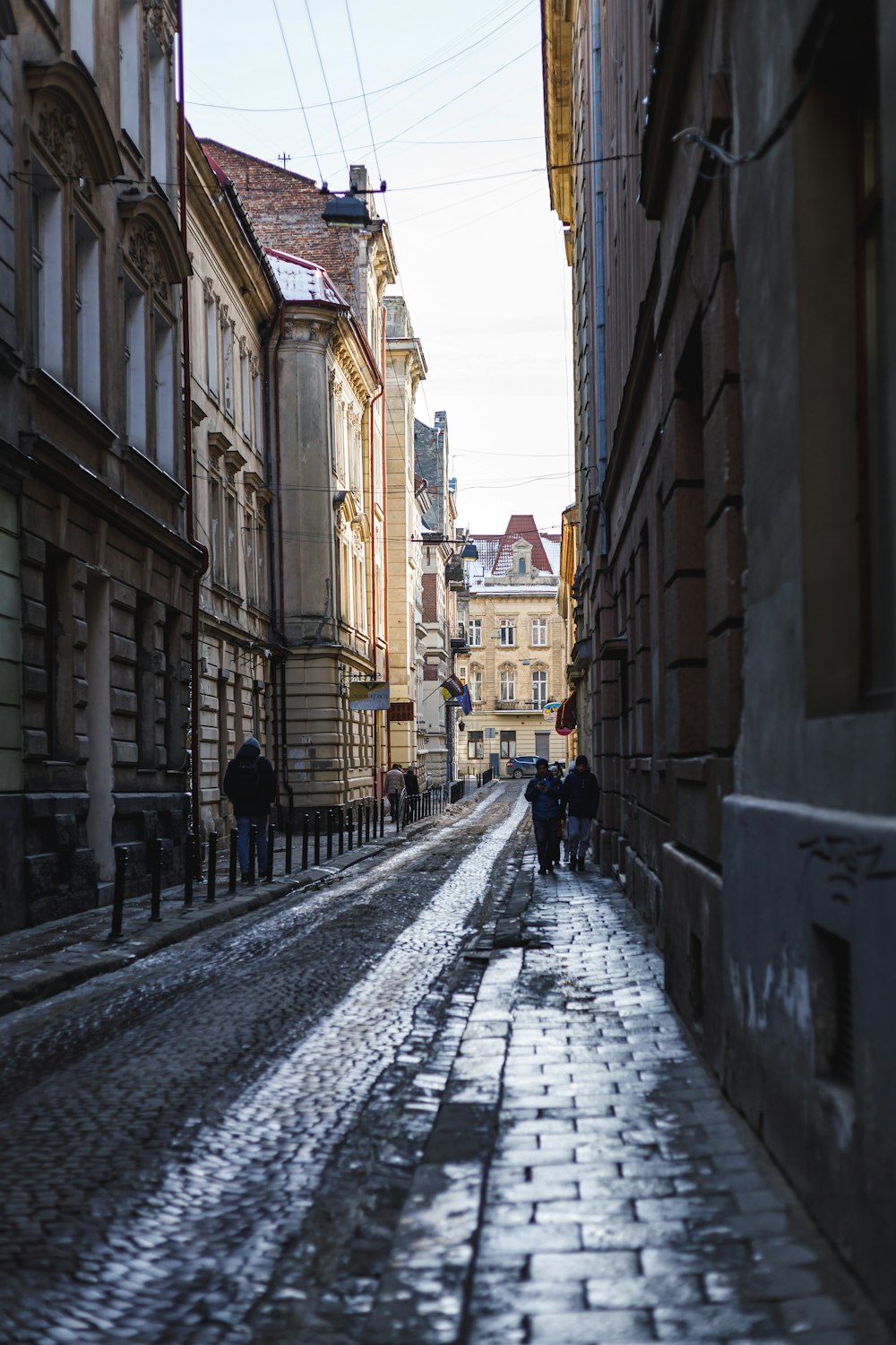 people walking down a cobblestone street in a city