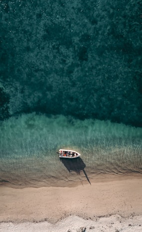 Close-up of a small, elegant boat available for rent without a license, anchored near a quiet beach.