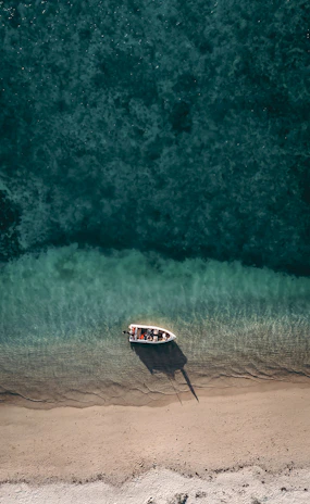 Sunset view of a small boat anchored near a turquoise beach in Cozumel.