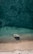 A serene view of a private yacht anchored near a sandy beach with clear blue waters.