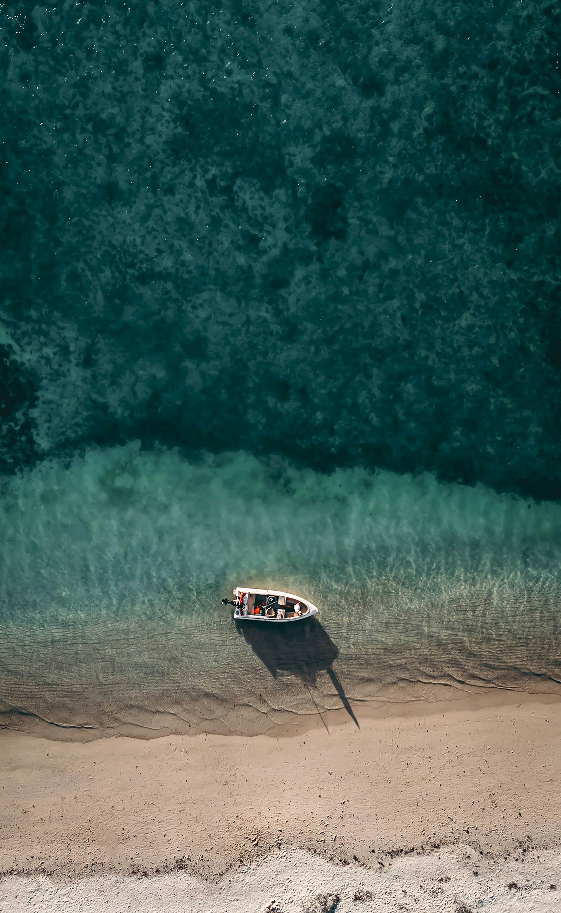 A panoramic view of a luxury boat anchored near a serene beach with turquoise water.