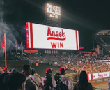 A scoreboard glowing under stadium lights with players celebrating.