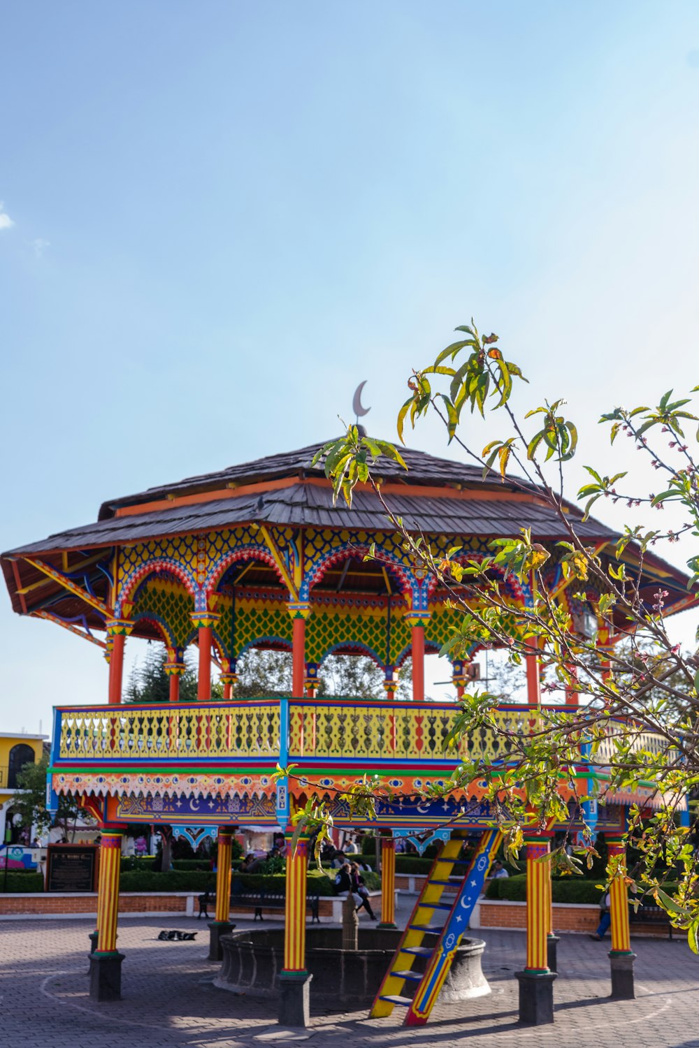 a colorful gazebo sits in the middle of a park