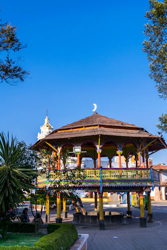 a gazebo in a park with a full moon in the background