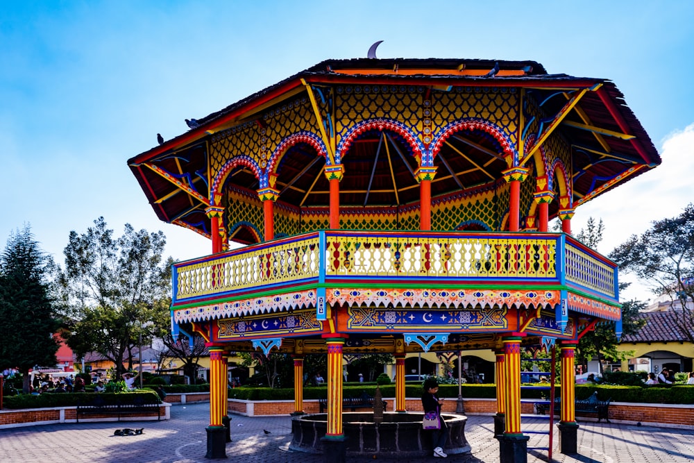 a colorful gazebo in a park with a blue sky in the background