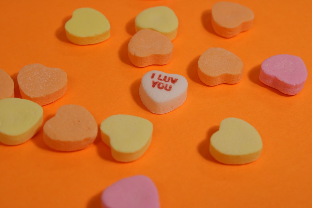 a group of conversation hearts sitting on top of an orange surface