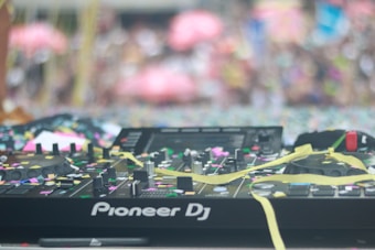 A DJ console is covered with colorful confetti and streamers. The background is blurred, suggesting a festive party atmosphere.