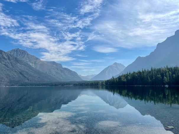 A tranquil lake reflecting the surrounding mountains and trees.