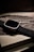 A sleek, modern smartwatch with a black ribbed band is placed on top of its packaging box, which shows an artistic wave design and the logo of the brand. The watch has a metallic casing and is presented at a slight angle, creating a sophisticated and luxurious appearance.