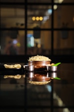 Close-up of a colorful pot filled with traditional Brazilian cuscuz topped with melted cheese and fresh herbs.