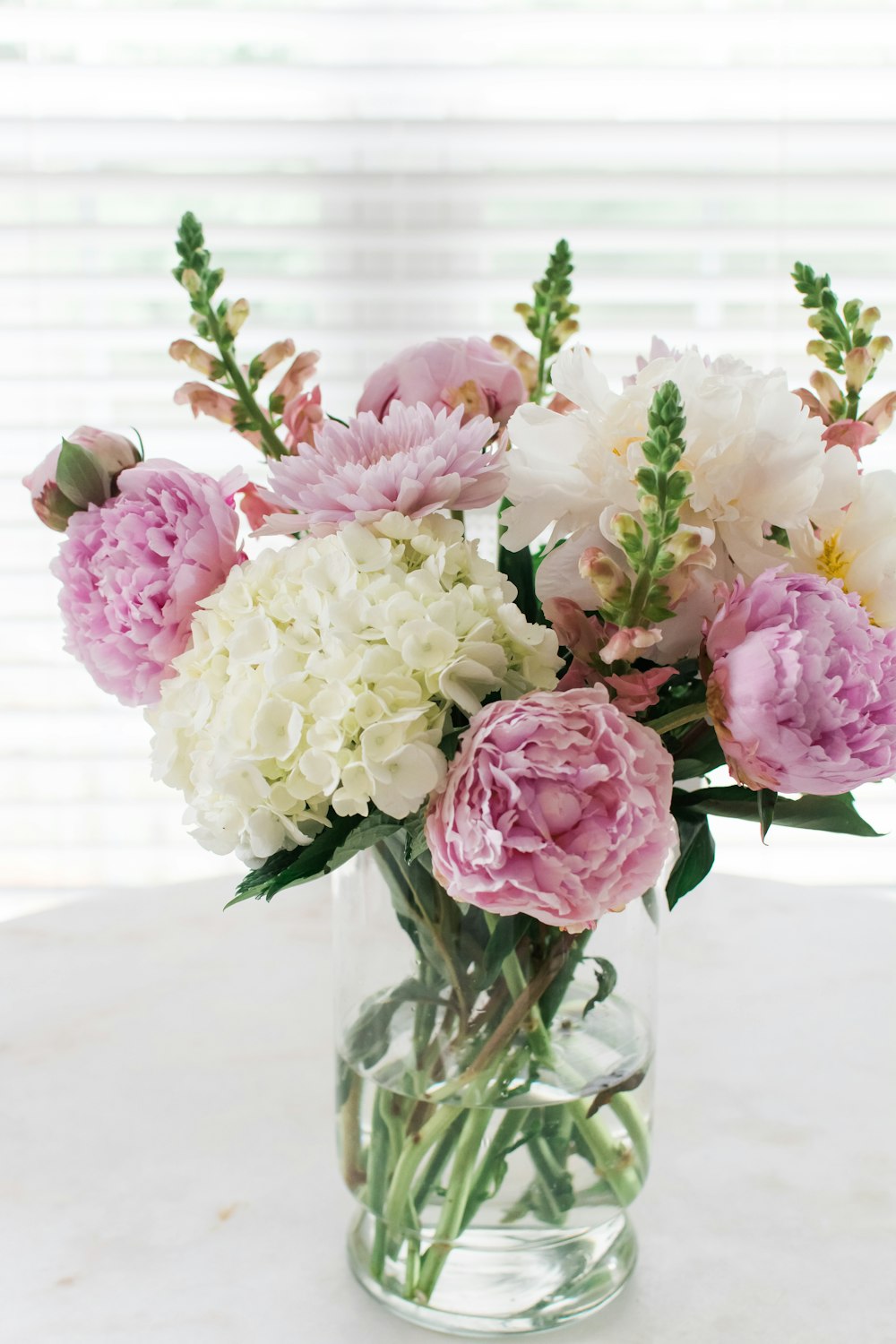 a vase filled with lots of pink and white flowers