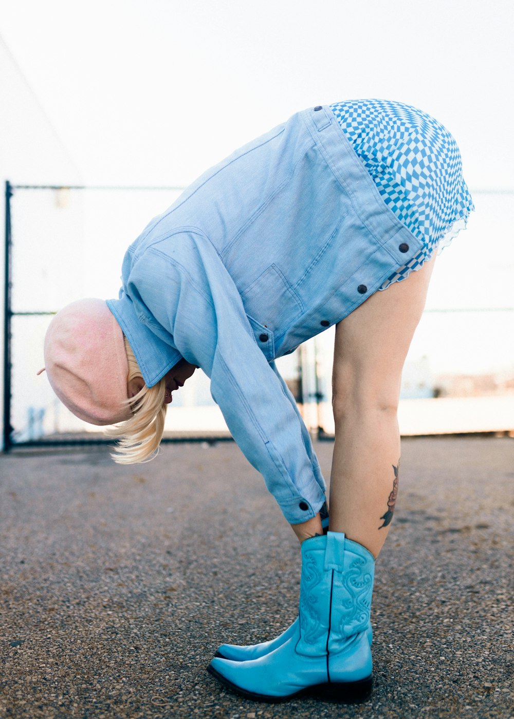 a person with a hat and blue boots doing a handstand
