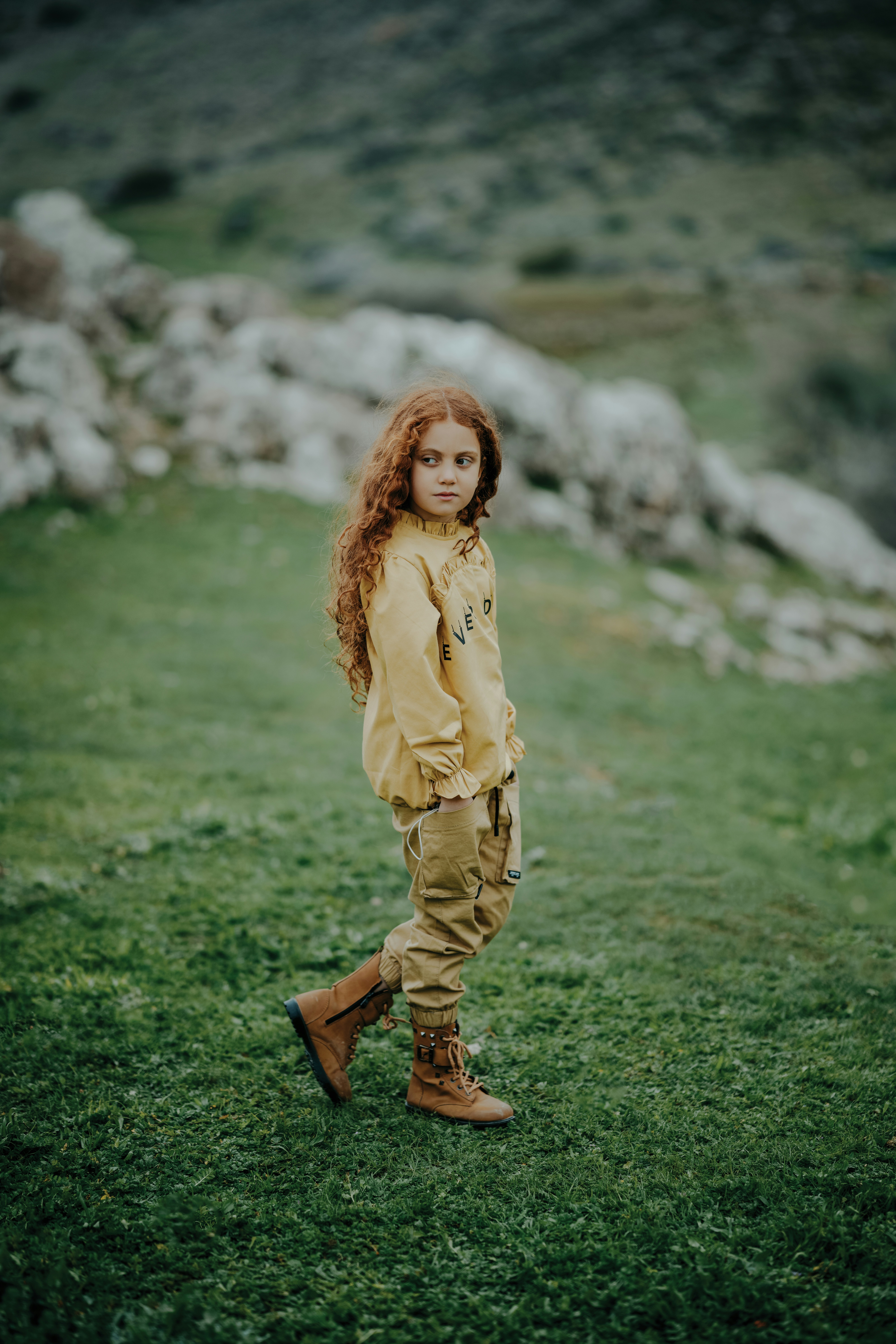A little girl standing on top of a lush green field photo – Free ...