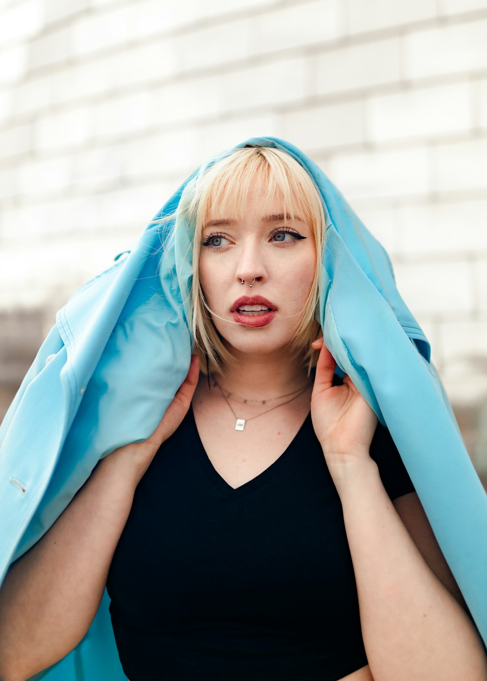 a woman in a black top is holding a blue jacket over her head
