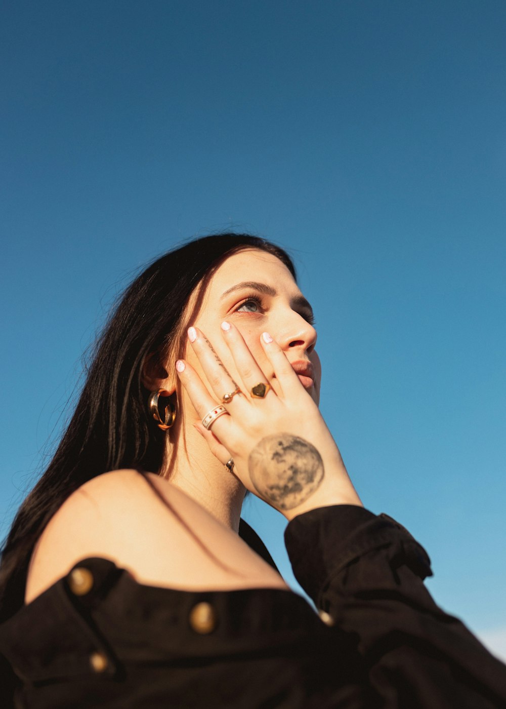 a woman with a tattoo on her arm holding her hand up to her face