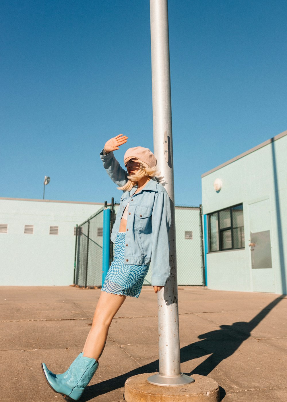 a woman leaning against a pole in a parking lot