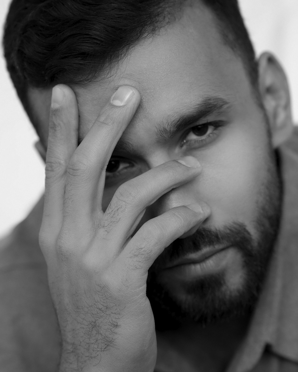 a black and white photo of a man holding his hand to his face