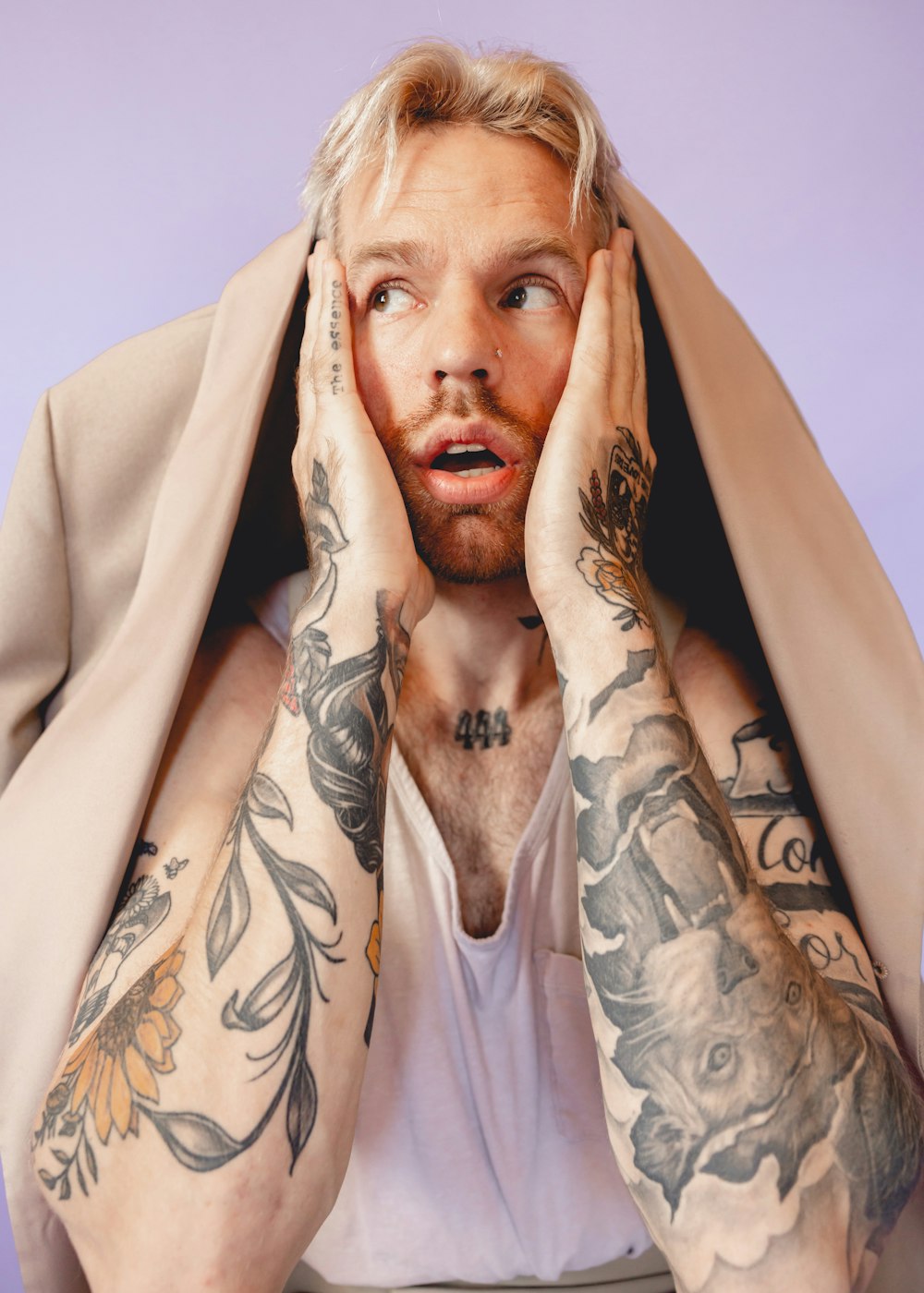 a man with tattoos covering his face with a blanket