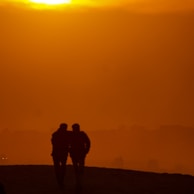 Sunset silhouette of a pilot instructor and student walking toward the hangar after a day of training.