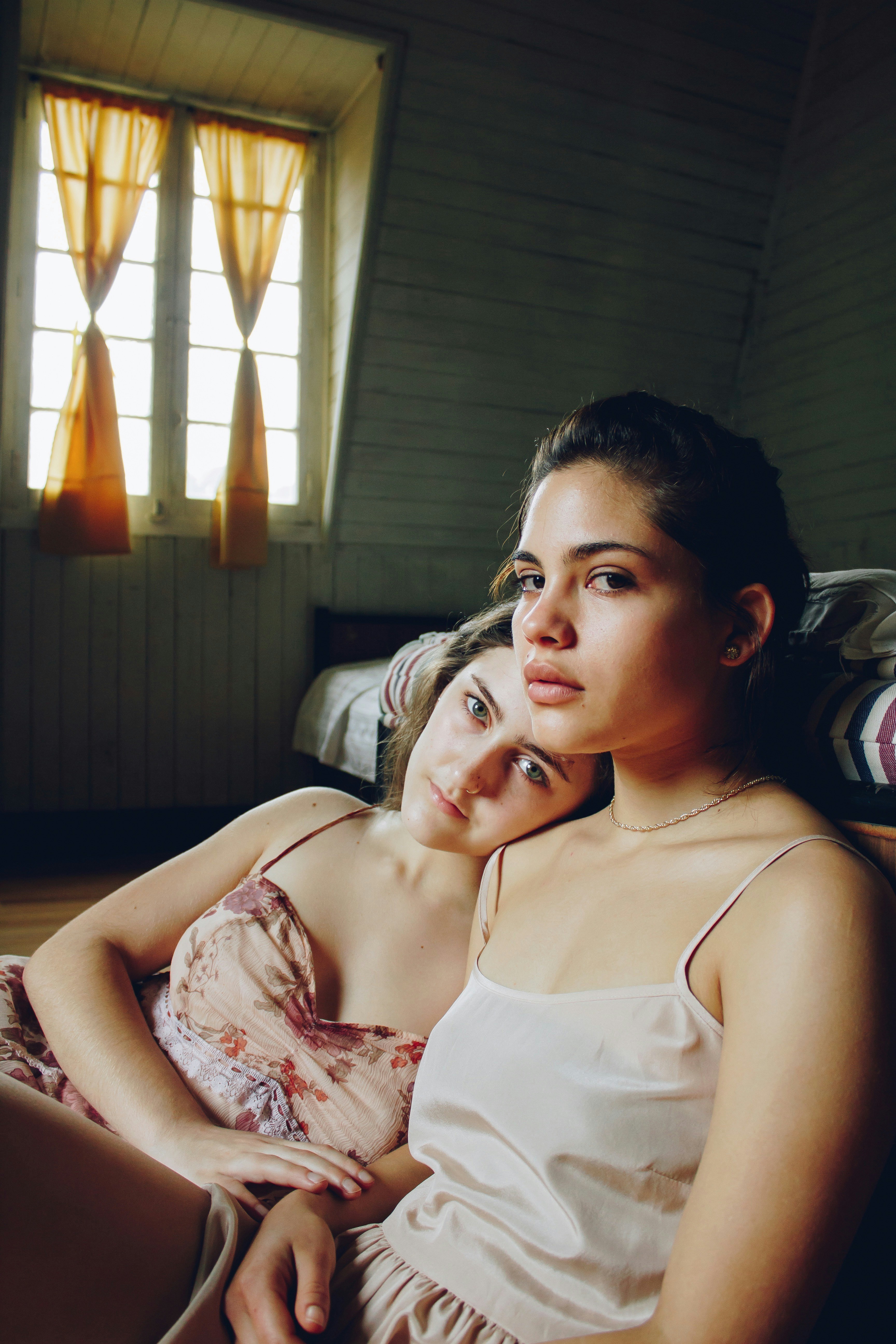 a couple of women laying on top of a bed