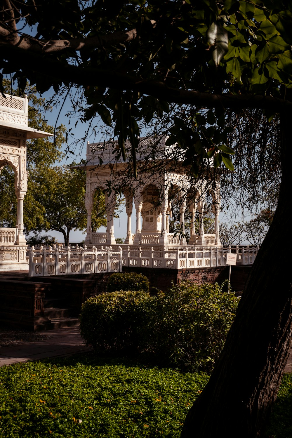 a white gazebo sitting next to a lush green park