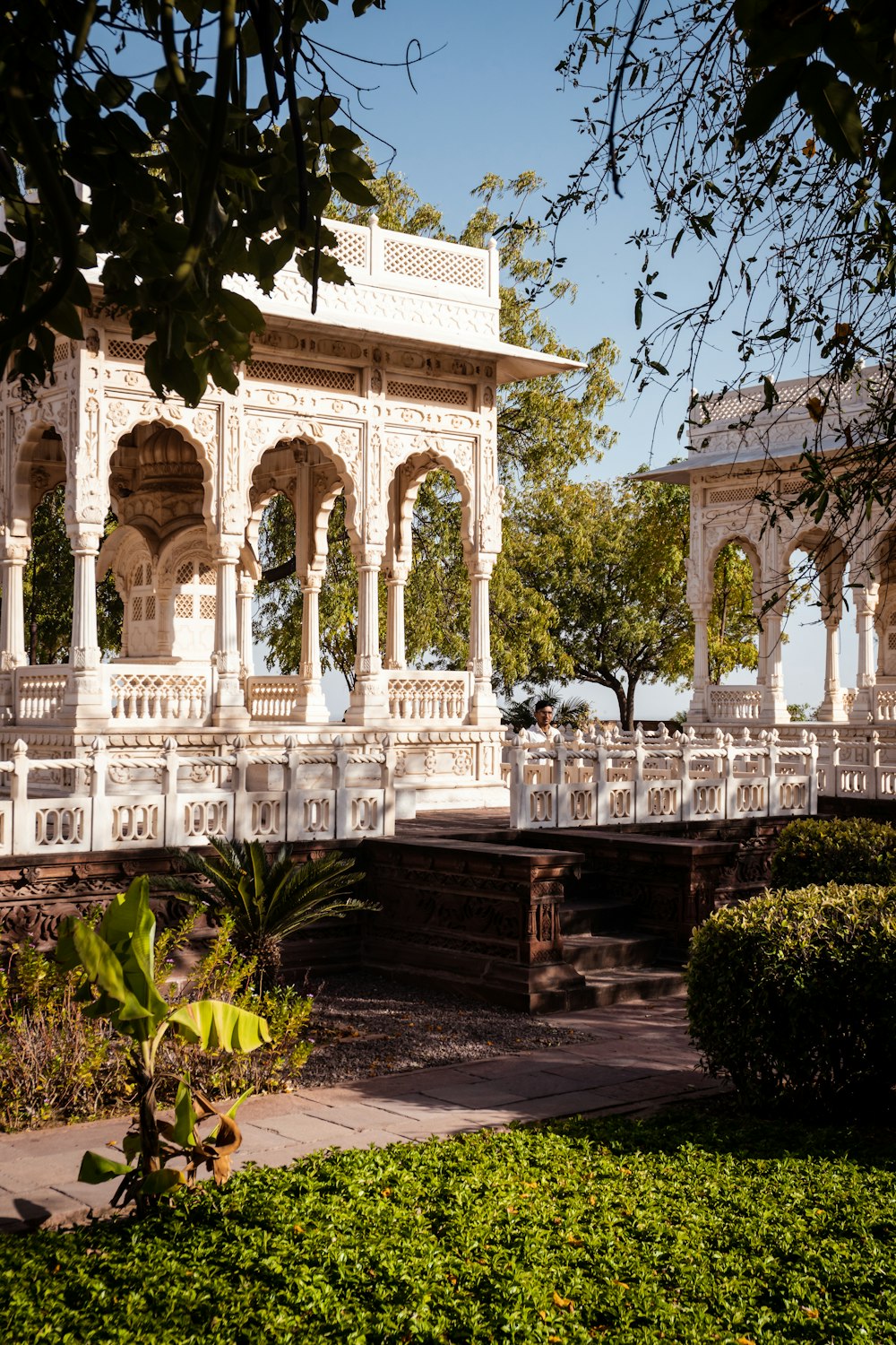 a white gazebo sitting next to a lush green park