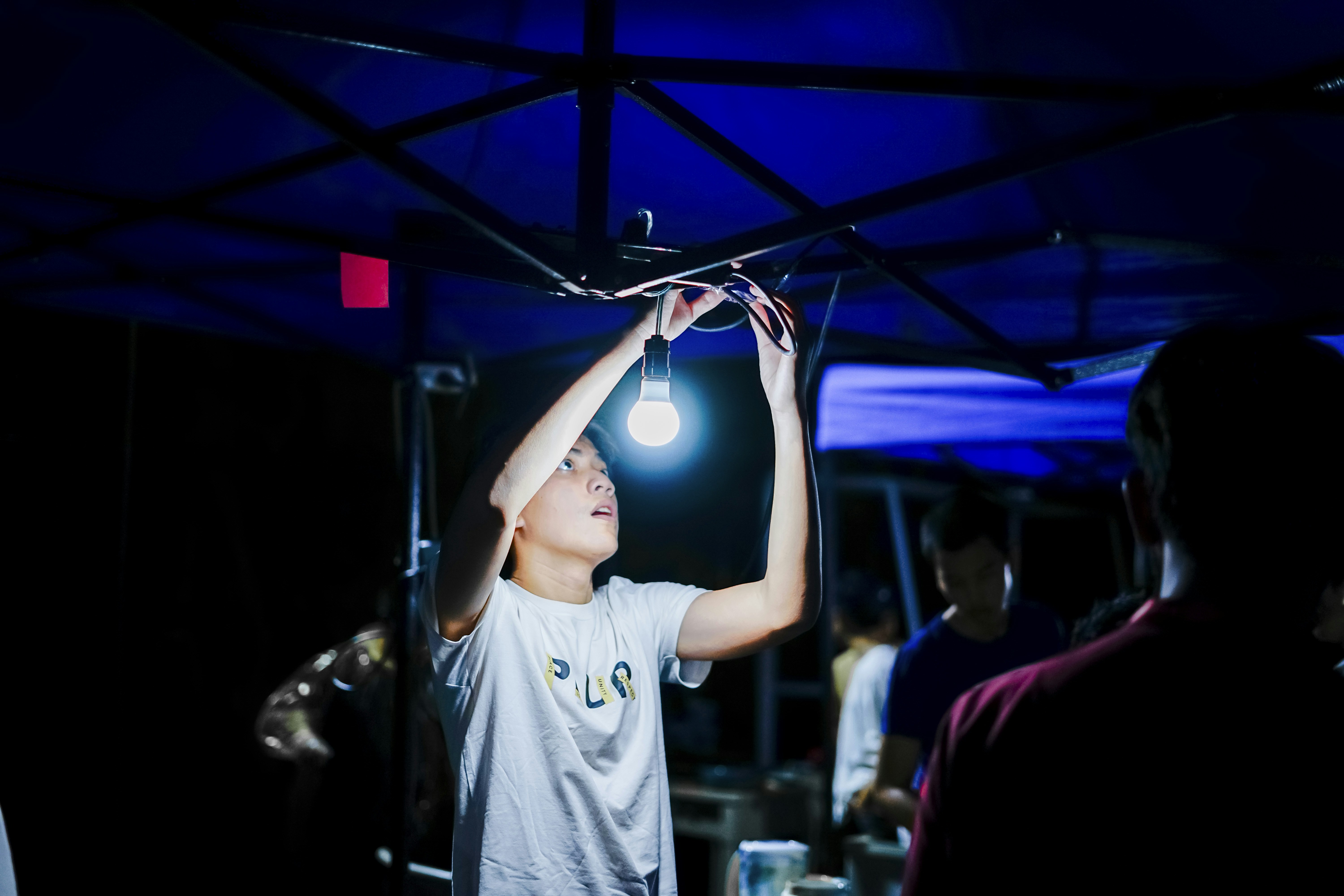a young boy holding a light bulb above his head