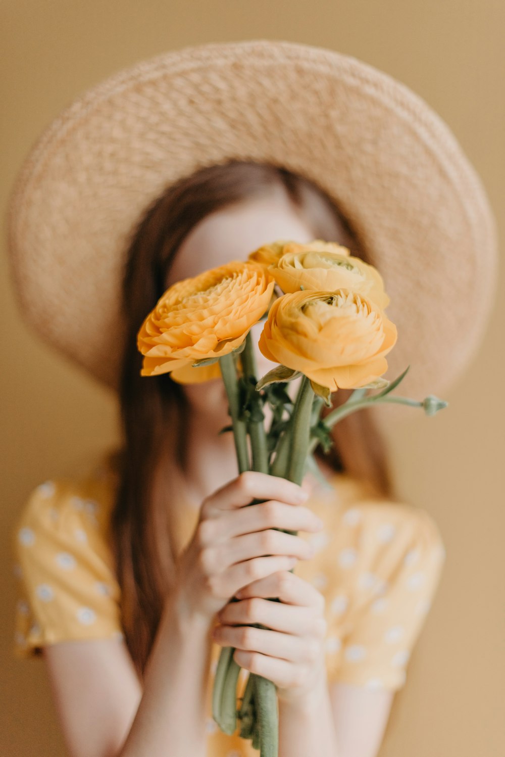 a woman in a straw hat holding a bunch of flowers