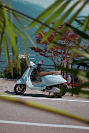 A vibrant scooter parked on a sunny coastal street in Atrani with the sea and cliffs in the background.