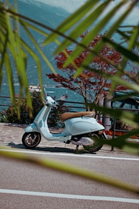 A vibrant scooter parked on a sunny coastal street in Atrani with the sea and cliffs in the background.