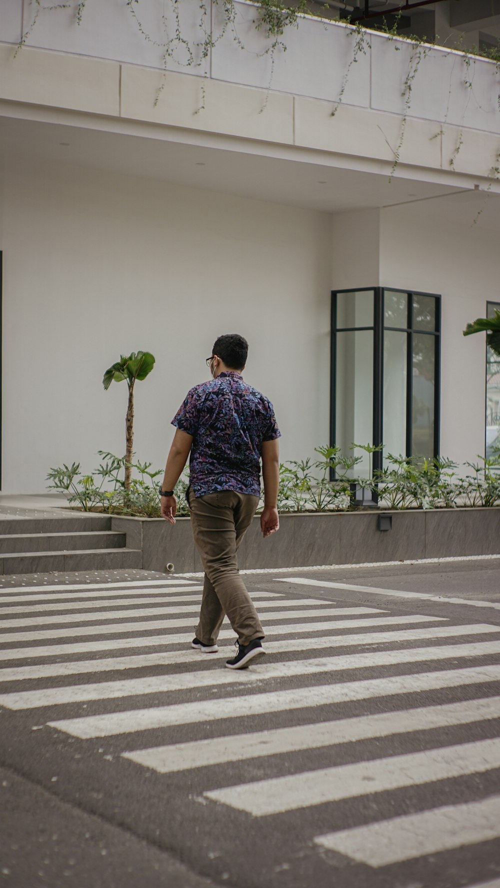 Un hombre caminando a través de un cruce de peatones frente a un edificio
