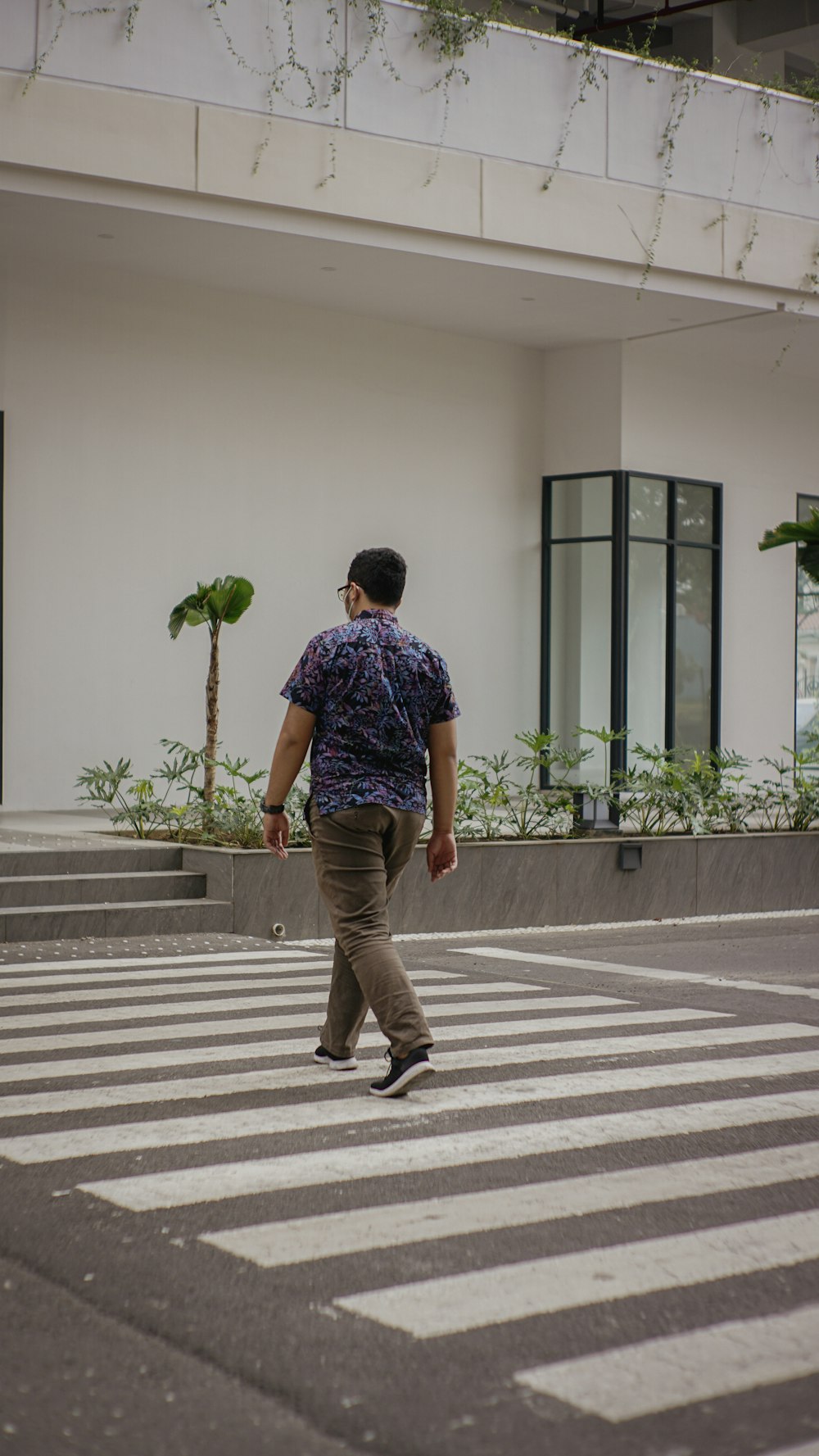 a man walking across a cross walk in front of a building